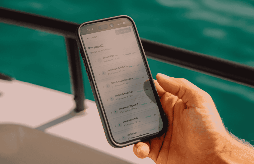 Theorie In Der Nautigo App: Smartphone Mit Lernfragen In Der Hand, An Bord Auf Dem Wasser
