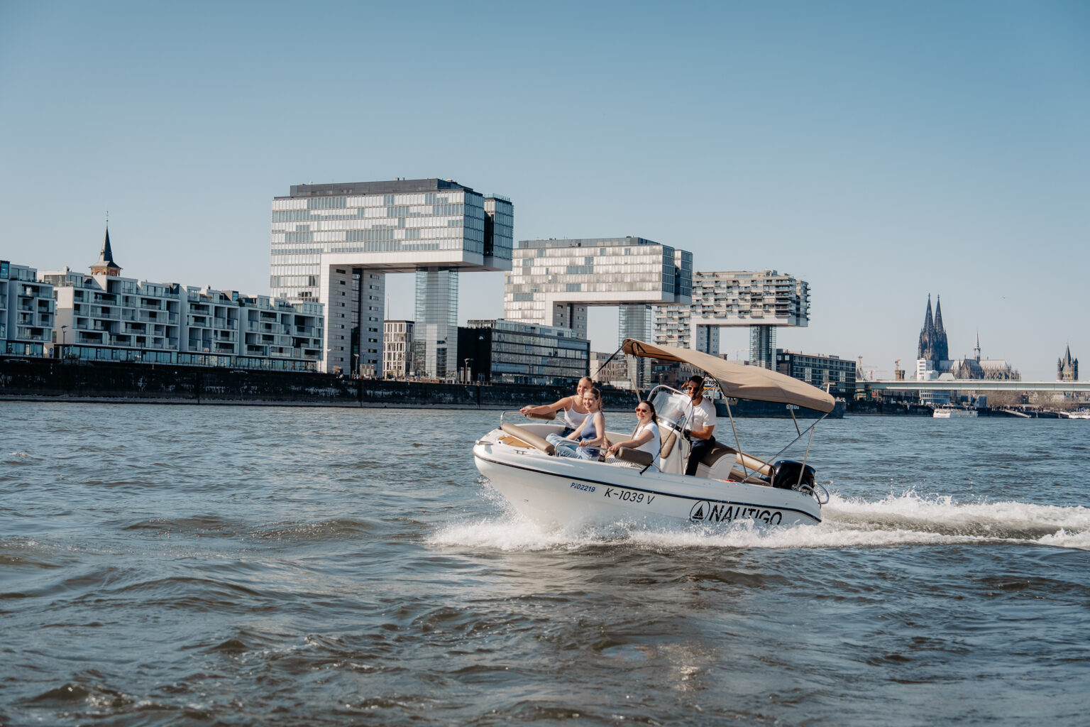 Nautigo Praxisausbildung: Sportboot in Fahrt vor den Kranhäusern und dem Dom auf dem Rhein bei Köln
